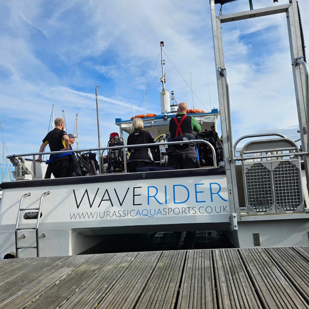 The dive boat Waverider, seen from the stern, up against the pontoon at the marina