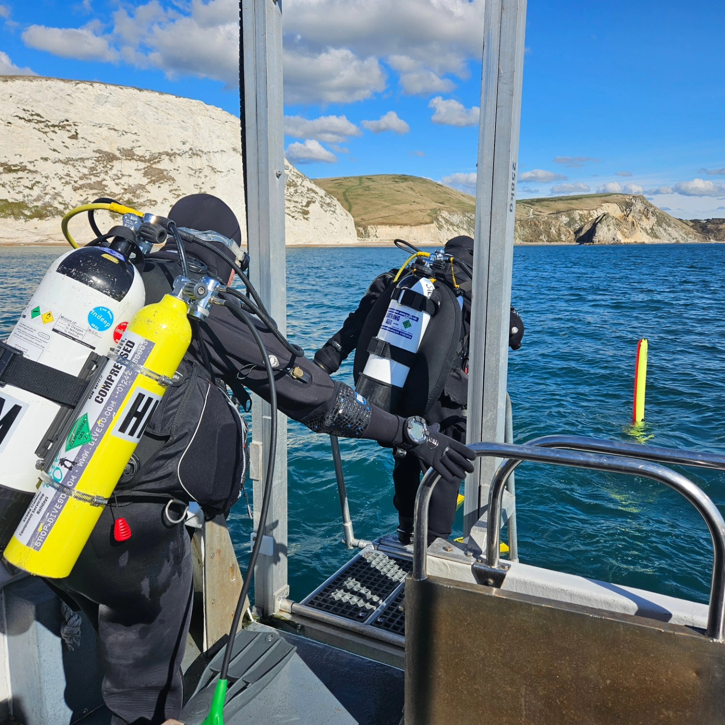 Two divers enter the water from the boat